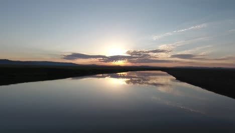 Luftdrohnenaufnahme,-Die-Einem-Fluss-Bei-Sonnenaufgang-In-Der-Mongolischen-Steppe-Folgt